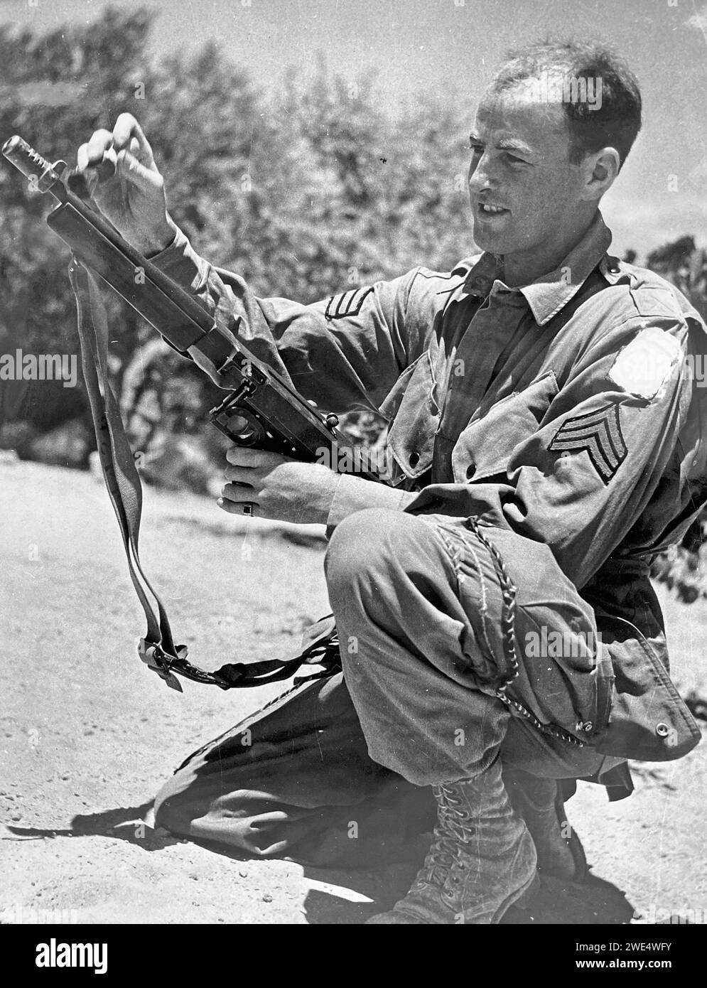 OPERATION HUSKY 1943. An American paratrooper checks his weapon prior to the airborne attacks on Sicily  in July. Stock Photo