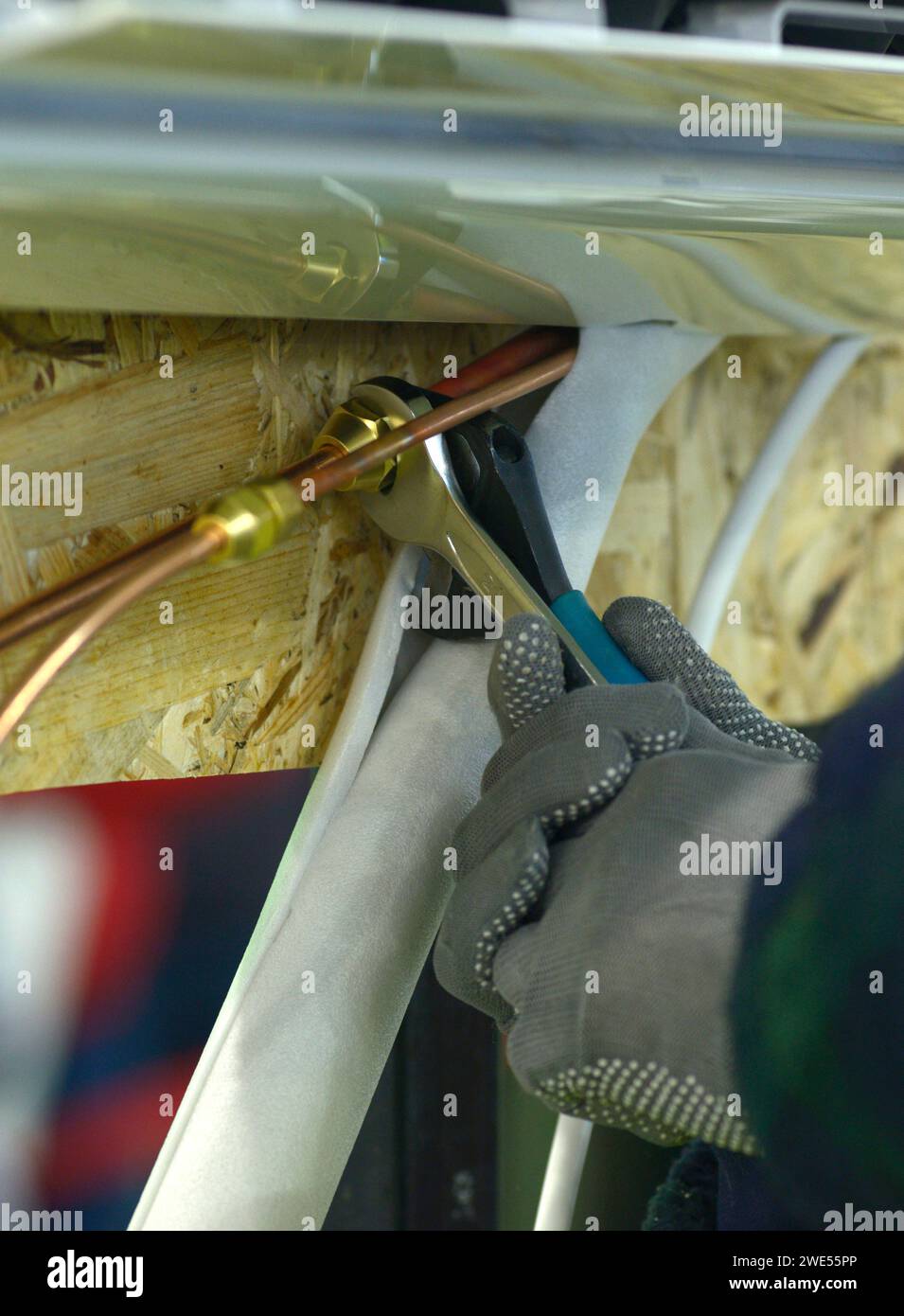 worker hands in gloves joining cooper pipes of an air conditioner using