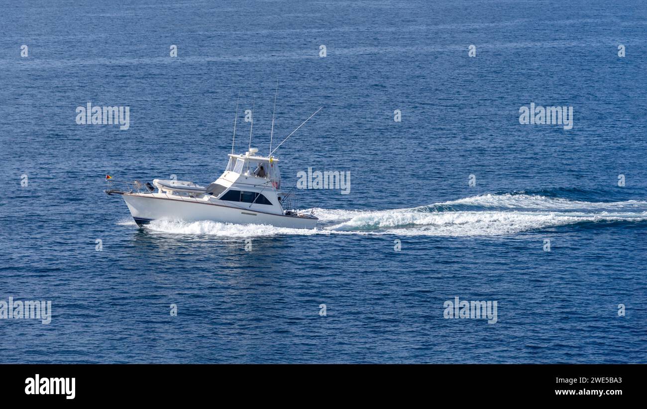 A white fishing boat speeding on the Pacific Ocean off the coast of