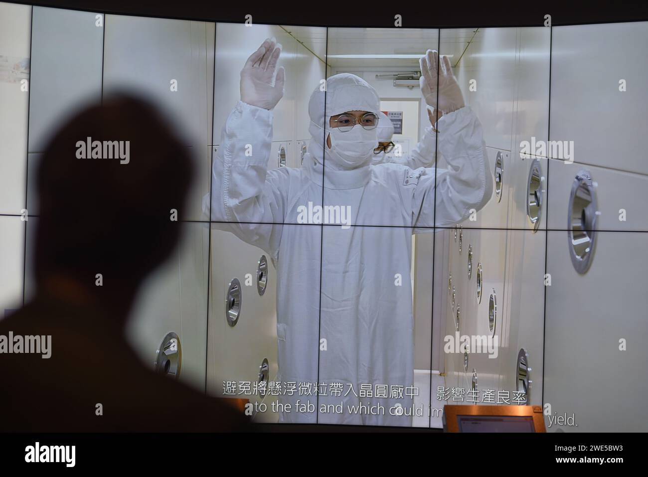 *** STRICTLY NO SALES TO FRENCH MEDIA OR PUBLISHERS - RIGHTS RESERVED ***October 06, 2023 - Hsinchu, Taiwan: A visitor of the TSMC Museum of Innovation watches a promotional video explaining how the Taiwan Semiconductor Manufacturing Company (TSMC) manufactures its integrated circuits and wafer semiconductor devices. On this screen grab, a TSMC employee goes through a decontamination room, as the work environment must remain completely clean. Stock Photo