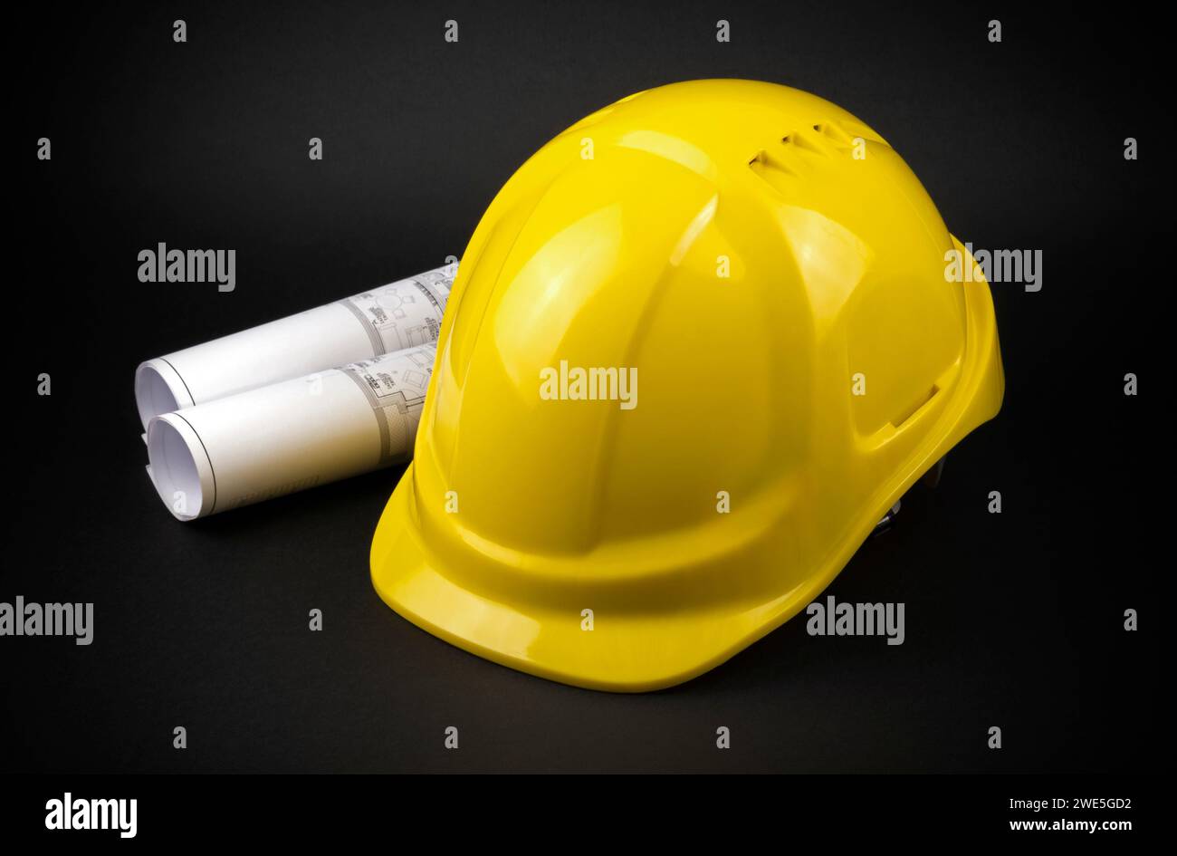Yellow safety hard hat with engineering drawings on dark background