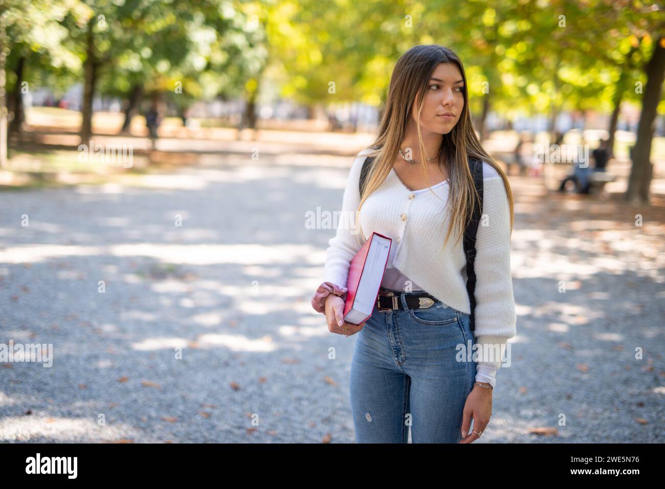 Smiling female college student walking outdoor in a park near the university Stock Photo