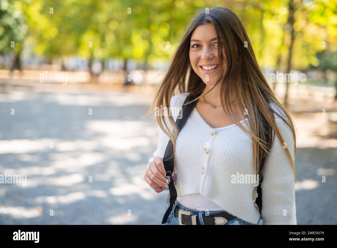 Smiling female college student walking outdoor in a park near the university Stock Photo