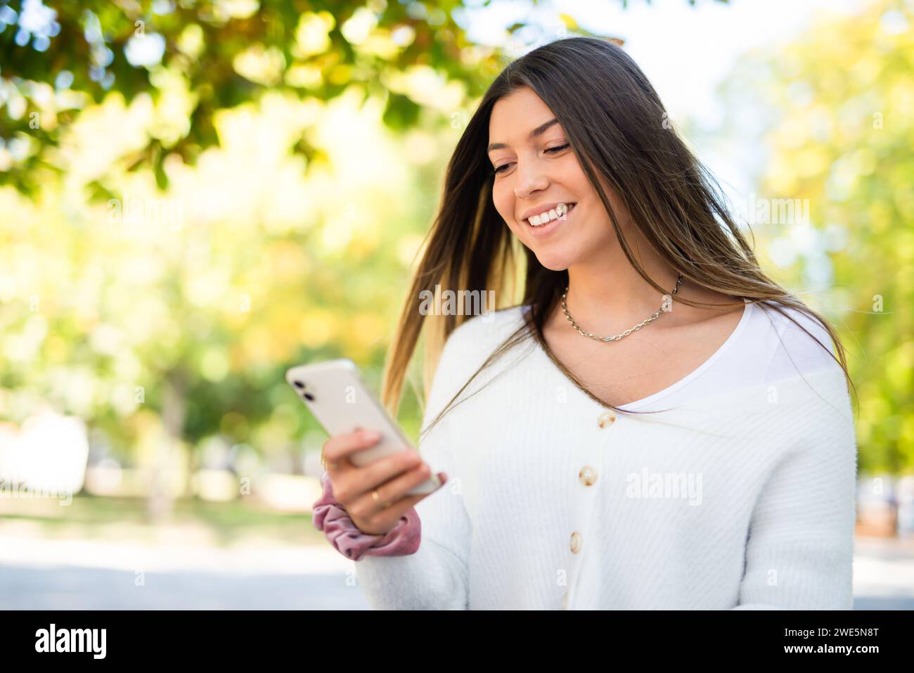 Woman walking in a park while using her smartphone Stock Photo