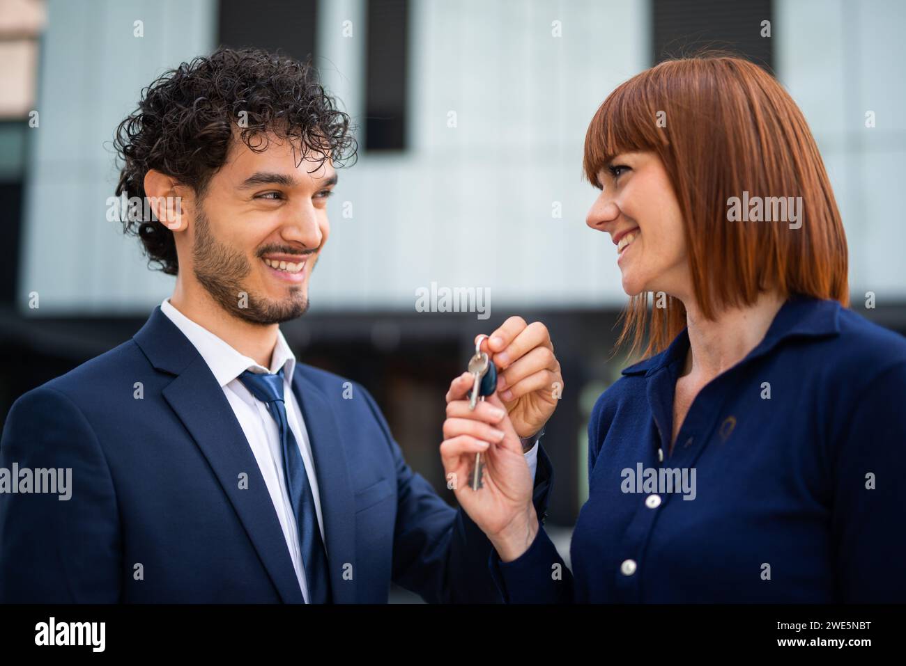 Businessman giving the keys of a new office to a businesswoman, real estate sale concept Stock Photo