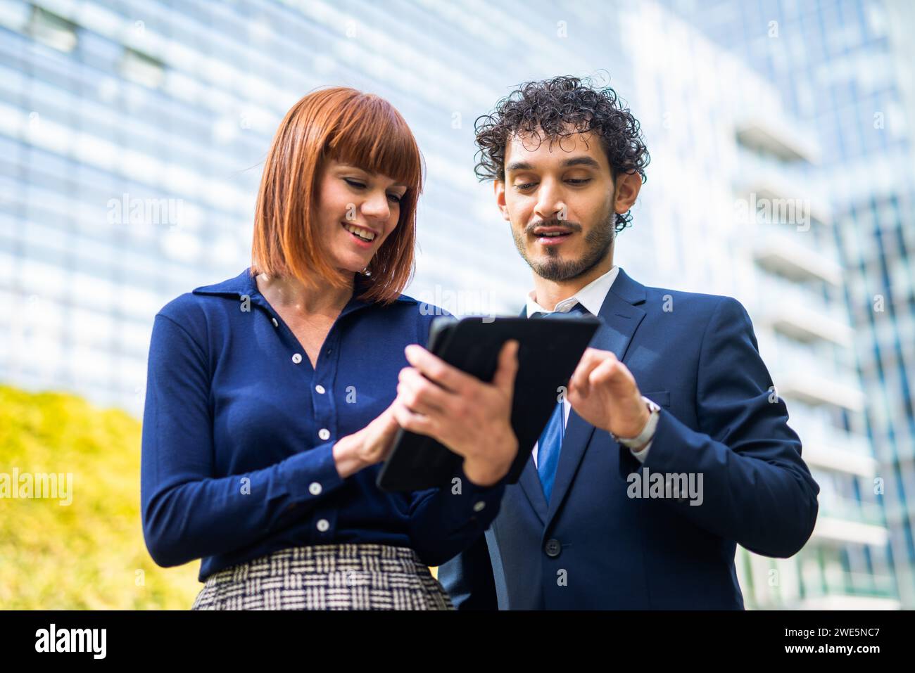 Businessman and businesswoman using a tablet together near a city park, ecology and business concept Stock Photo