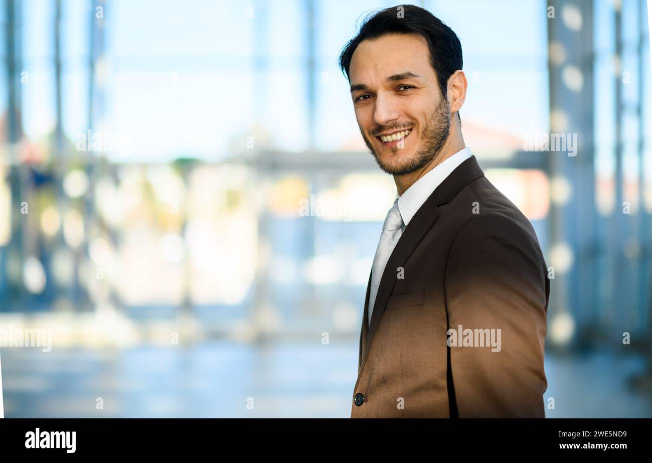 Portrait of a confident young adult caucasian businessman smiling and looking professional in business attire outdoors in an urban city. With an offic Stock Photo