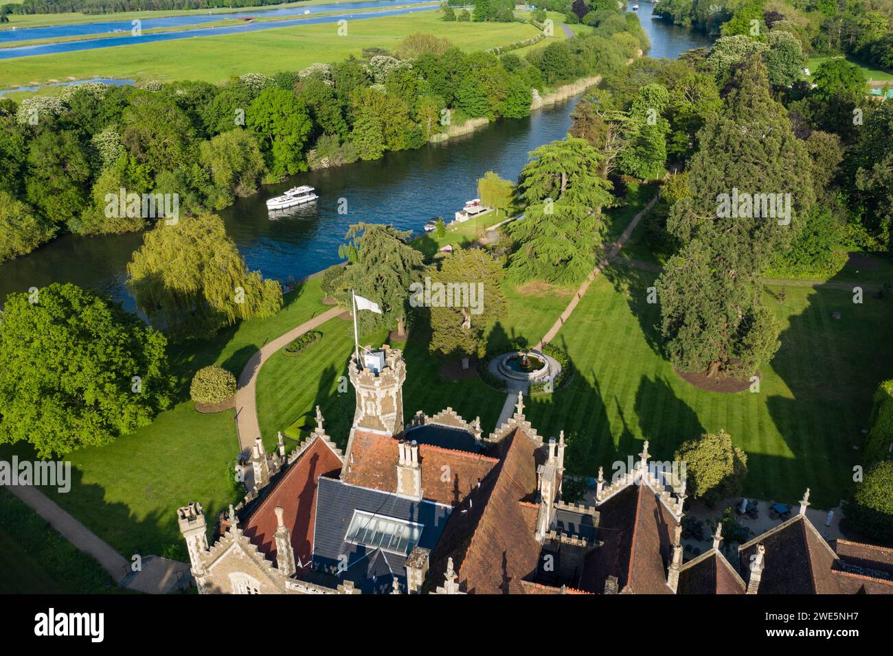 Aerial view of a Le Boat Horizon 4 houseboat passing the Oakley Court Hotel along the River Thames, Water Oakley, near Windsor, Berkshire, England, Un Stock Photo