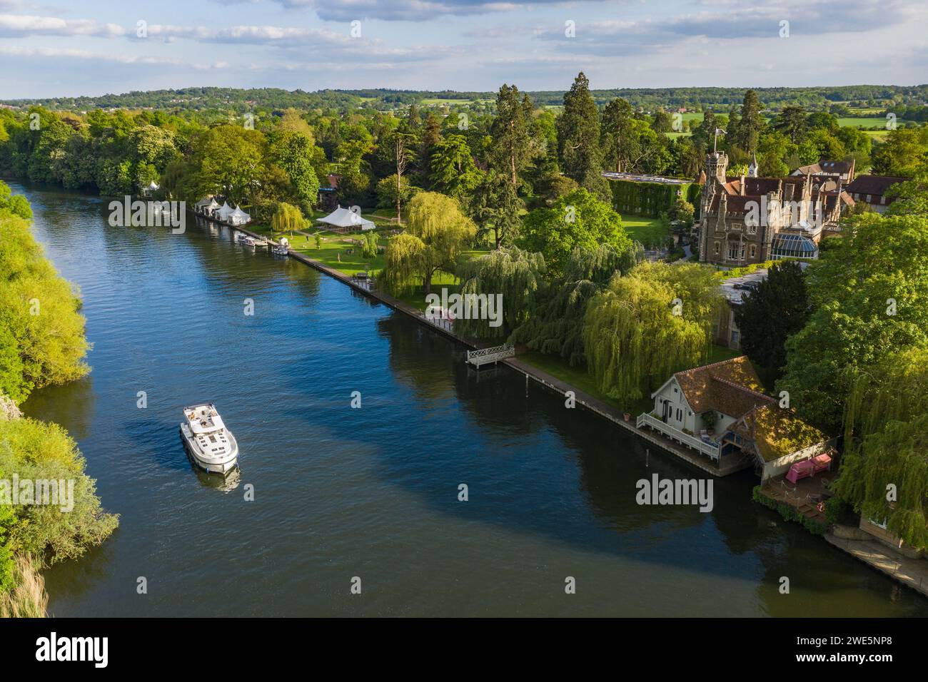 Aerial view of a Le Boat Horizon 4 houseboat passing the Oakley Court Hotel along the River Thames, Water Oakley, near Windsor, Berkshire, England, Un Stock Photo