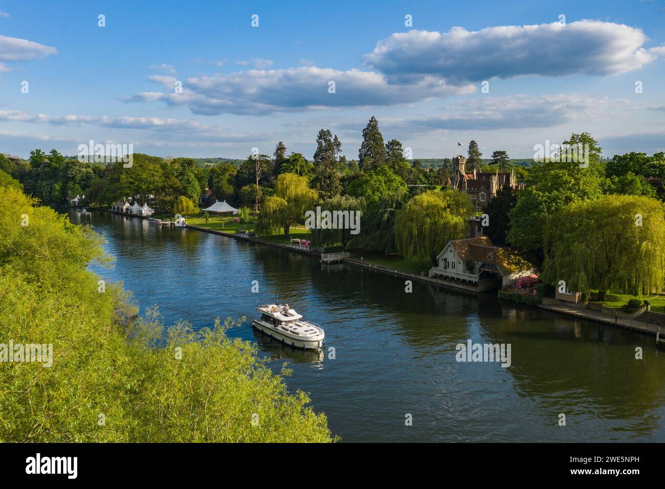 Aerial view of a Le Boat Horizon 4 houseboat passing the Oakley Court Hotel along the River Thames, Water Oakley, near Windsor, Berkshire, England, Un Stock Photo