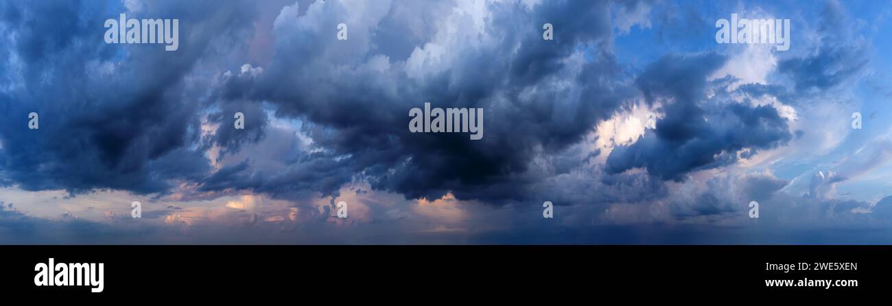 Dramatic sky background with dark rainy clouds at sunset. Stock Photo