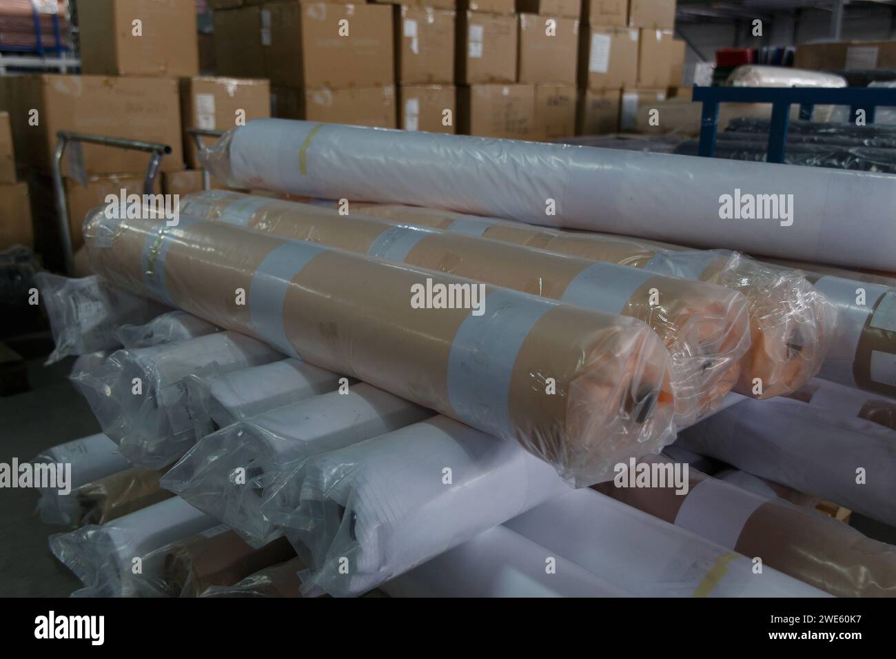 Rolls of white fabric and textiles in a factory warehouse. Stock Photo