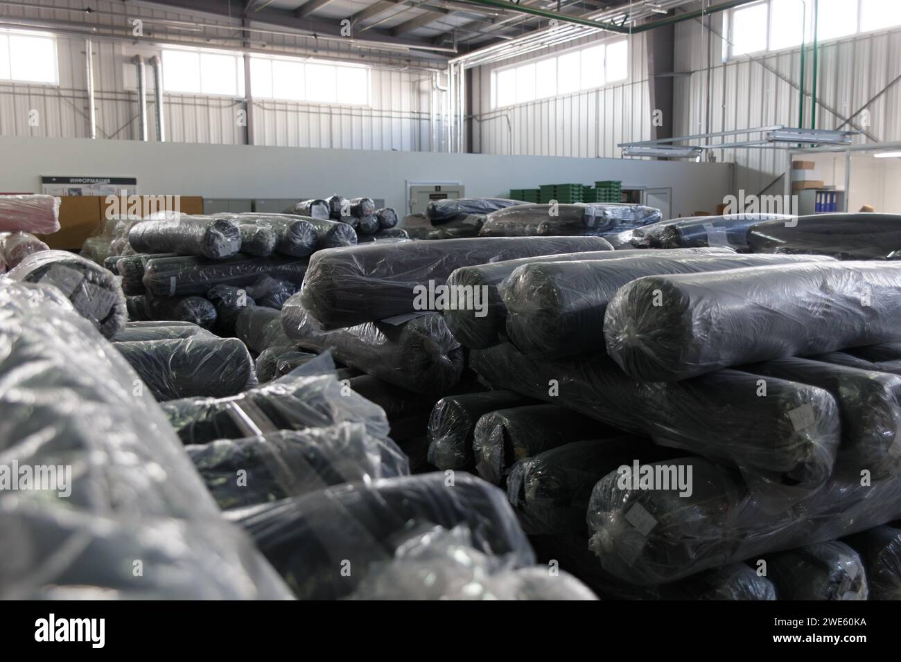 Rolls of black fabric and textiles in a factory warehouse. Stock Photo
