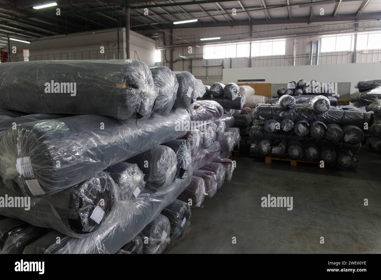 Rolls of black fabric and textiles in a factory warehouse. Stock Photo