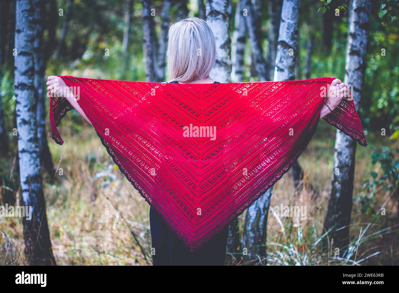 Fourty years old woman show hand crochet made by herself ombre shawl in birch grove Stock Photo