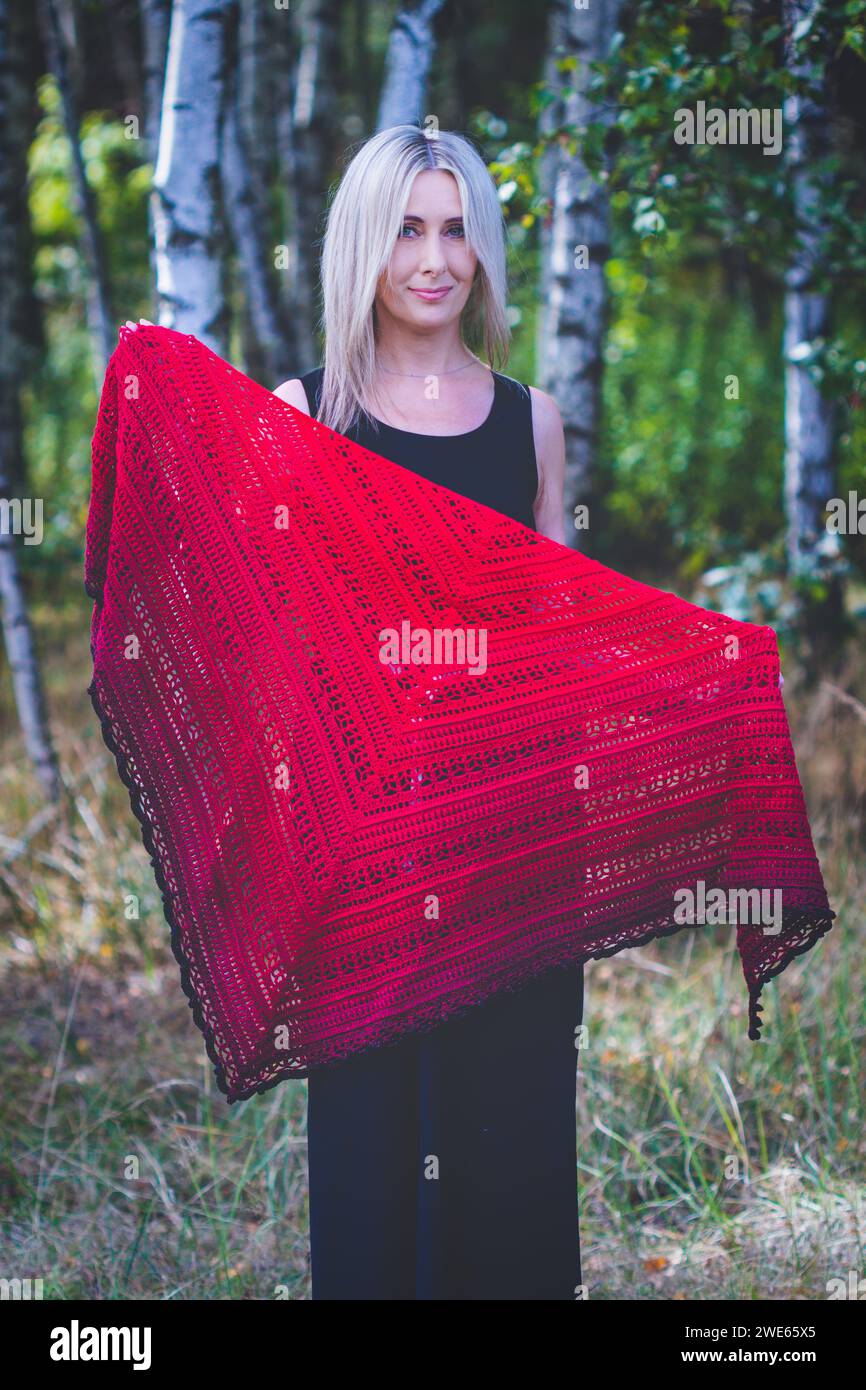 Fourty years old woman show hand crochet made by herself ombre shawl in birch grove Stock Photo