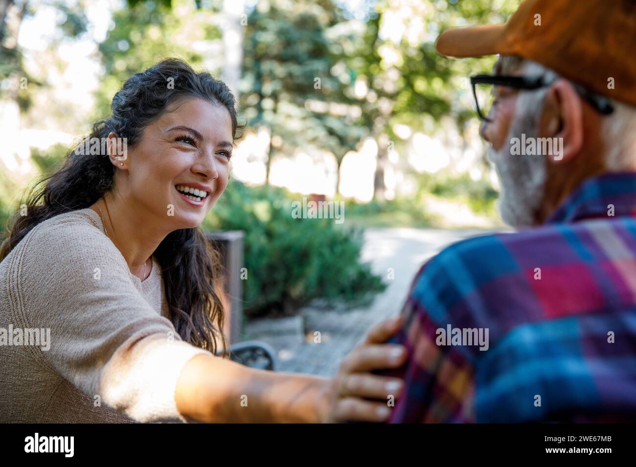 Happy caregiver consoling retired senior man at park Stock Photo