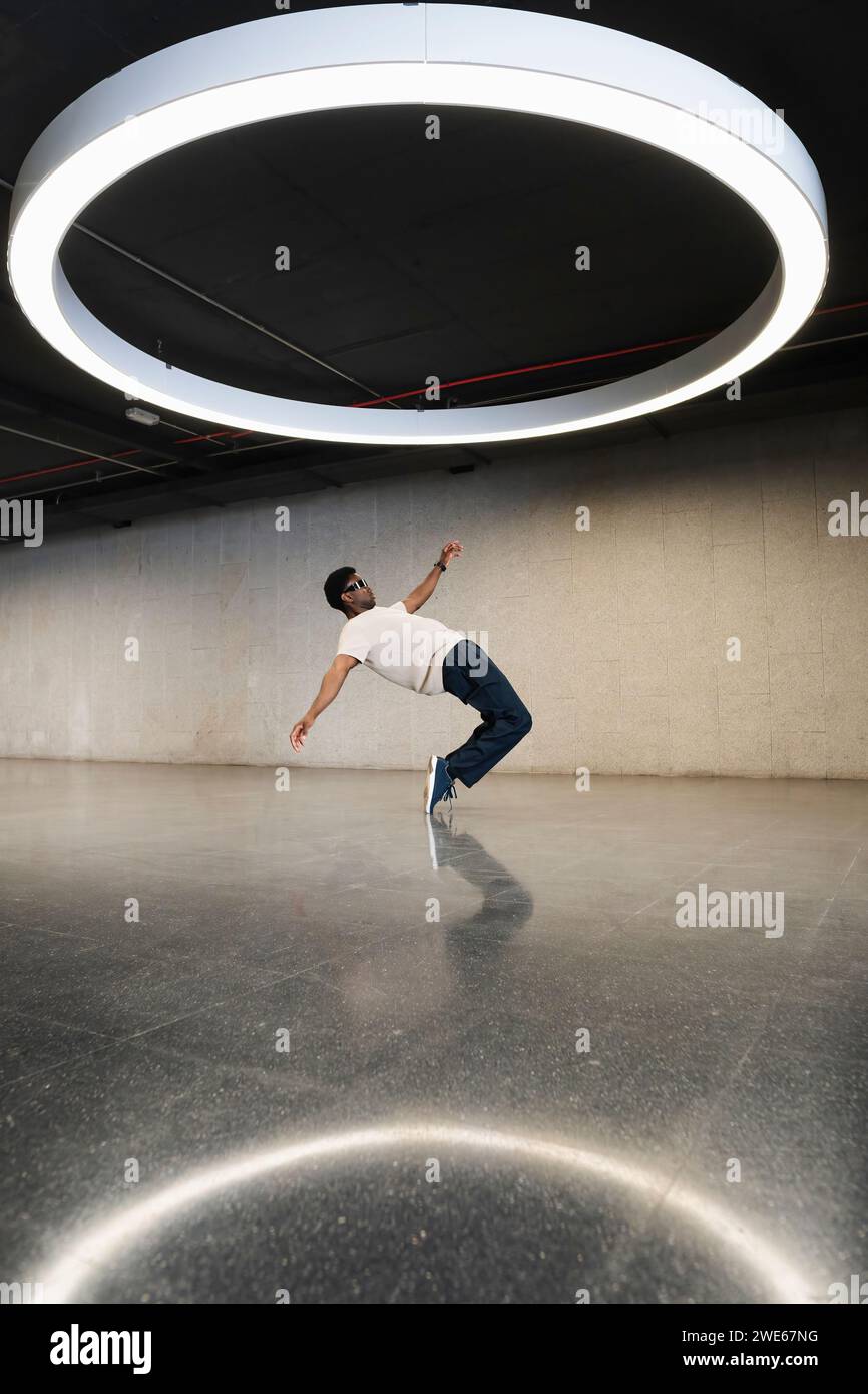 Young man with futuristic cyber glasses break dancing under modern ring lamp Stock Photo