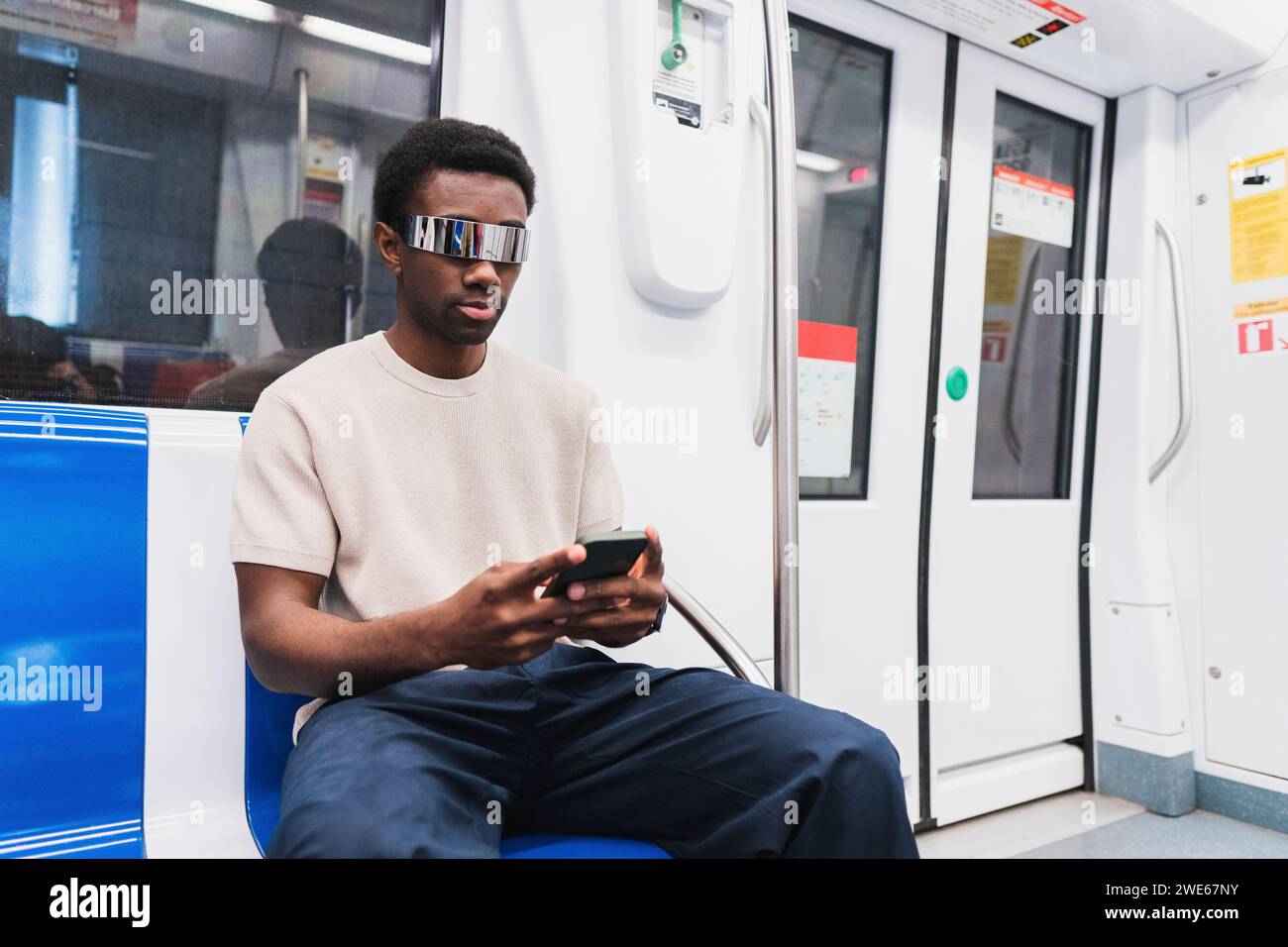 man with cyber glasses using smartphone sitting in metro Stock Photo