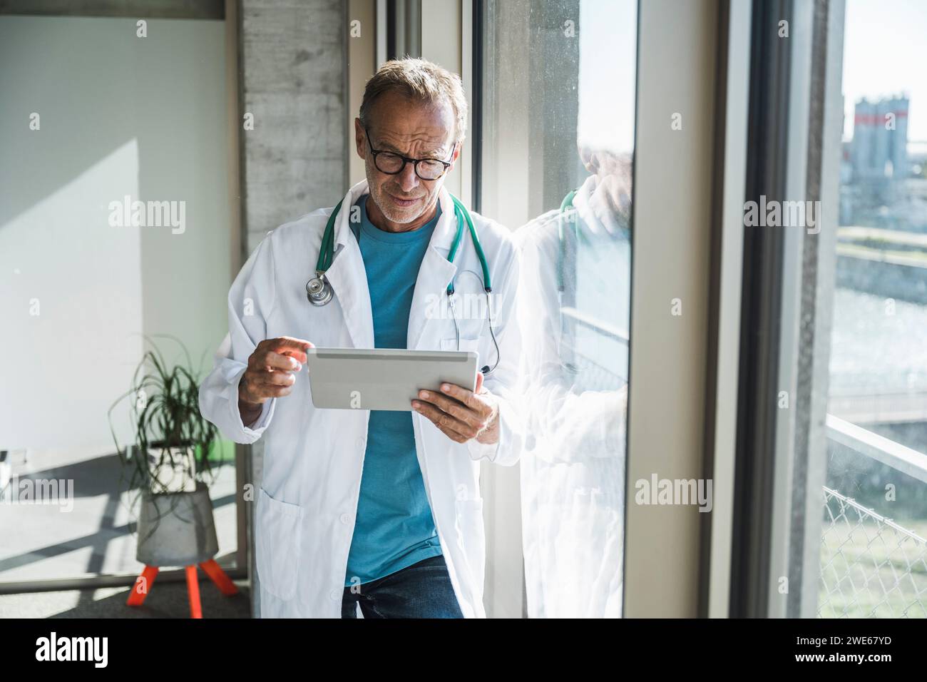 Senior doctor using tablet PC near window Stock Photo