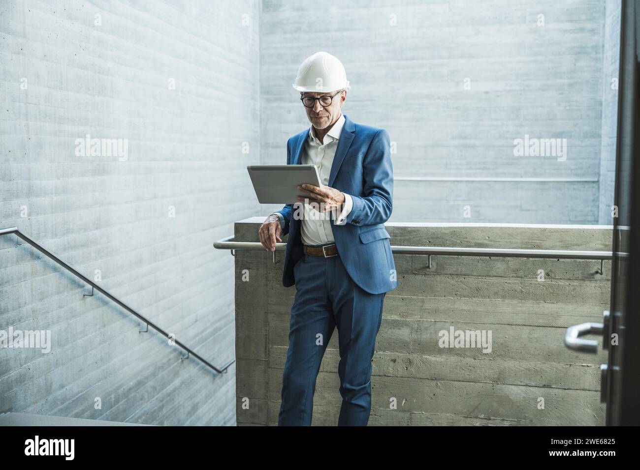 Senior engineer wearing hardhat and using tablet PC near wall Stock Photo