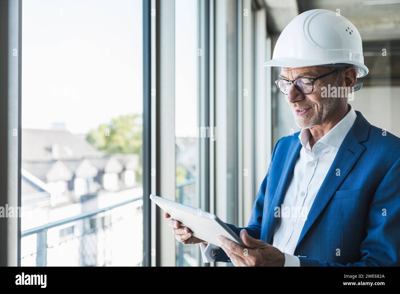 Smiling engineer using tablet PC near window Stock Photo