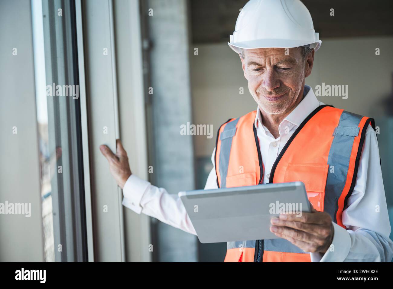 Smiling senior engineer using tablet PC near window Stock Photo