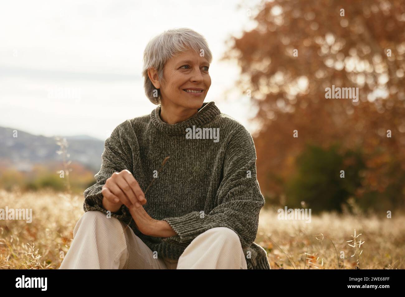 Woman sitting on dry grass hi-res stock photography and images - Alamy