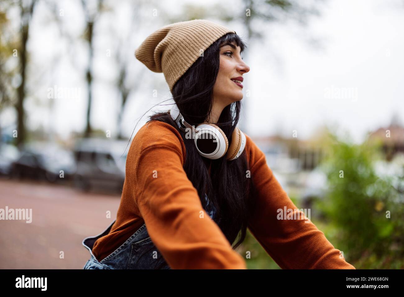 Happy woman with wireless headphones and knit hat Stock Photo