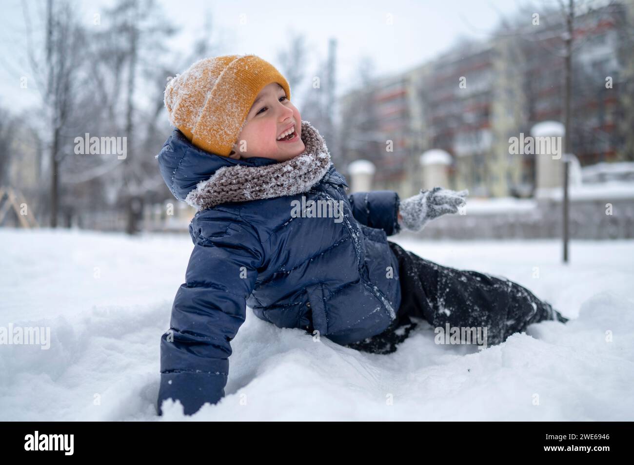 Happy boy enjoying in snow in park Stock Photo