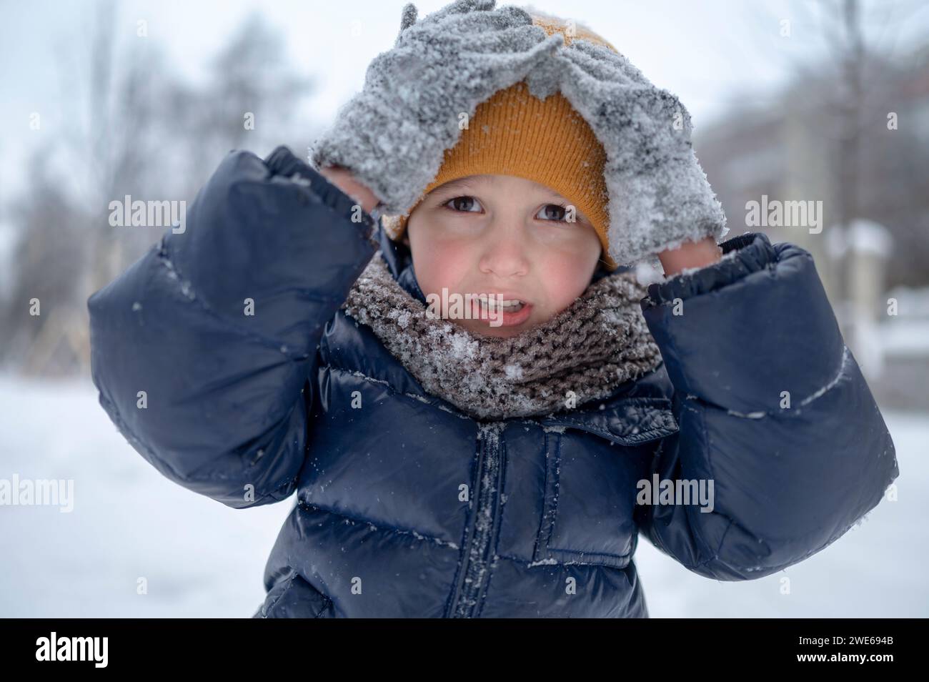 Boy touching yellow knit hat in winter Stock Photo