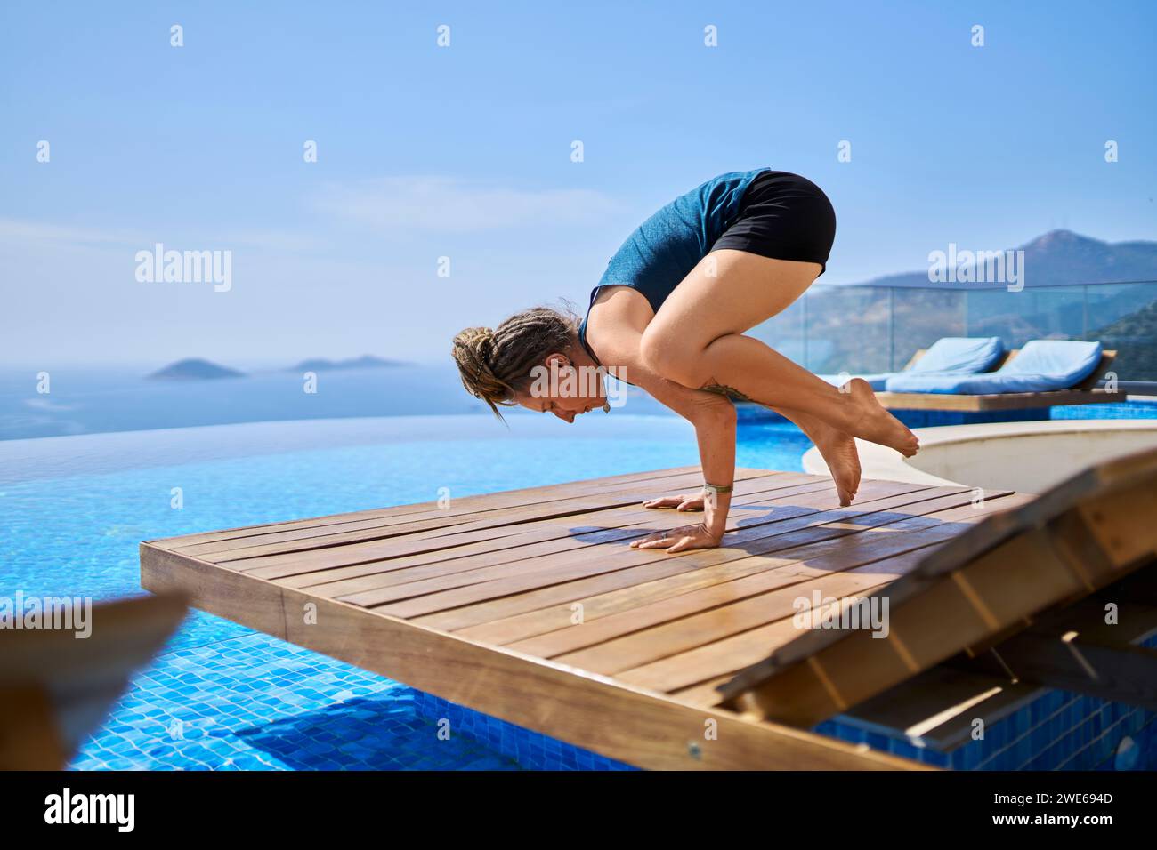 https://c8.alamy.com/comp/2WE694D/woman-doing-yoga-on-deck-chair-near-swimming-pool-2WE694D.jpg