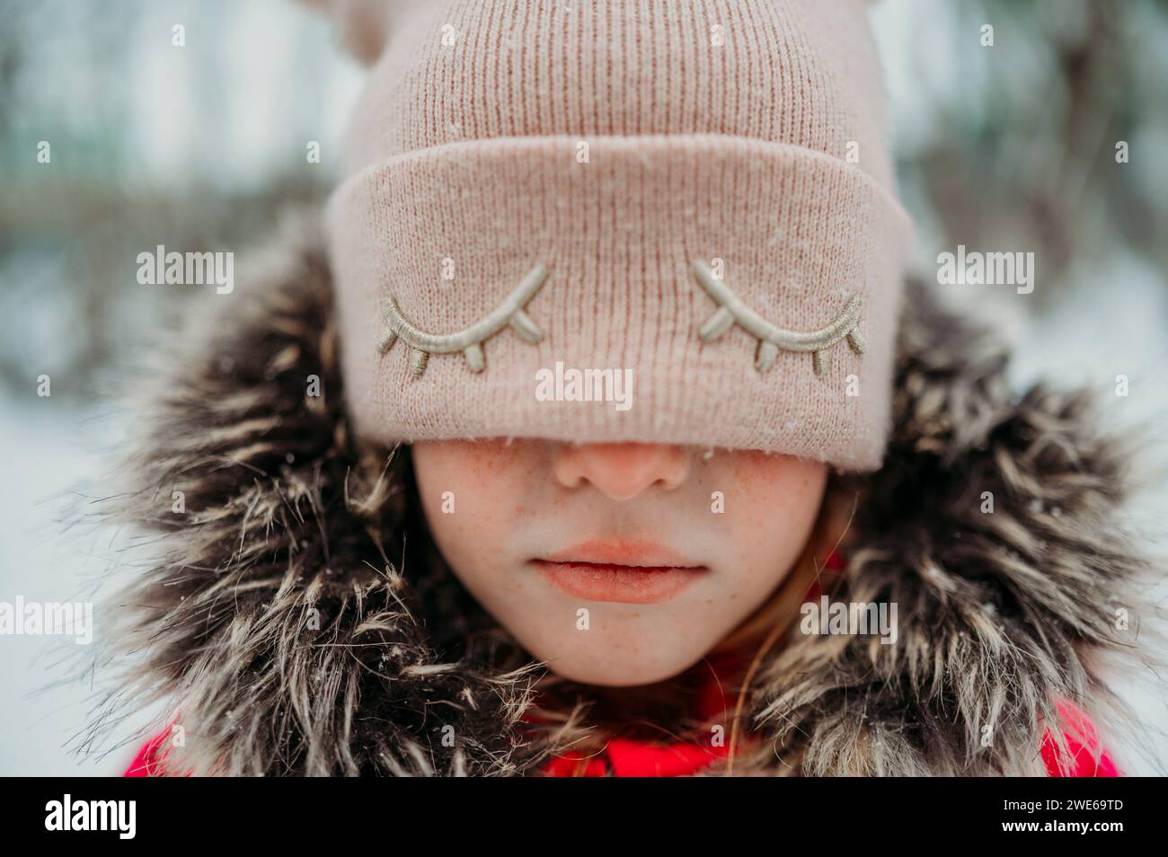 Sad girl covering eyes with pink knit hat Stock Photo