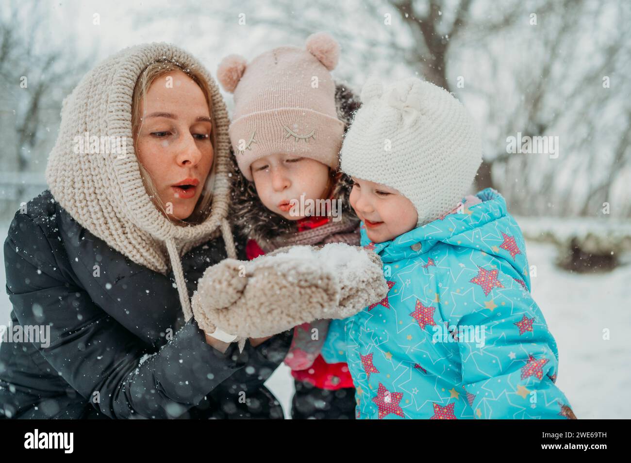 Mother and daughters blowing snow in winter park Stock Photo - Alamy