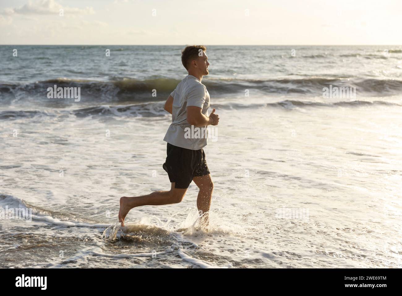 Man running in sea water at beach Stock Photo