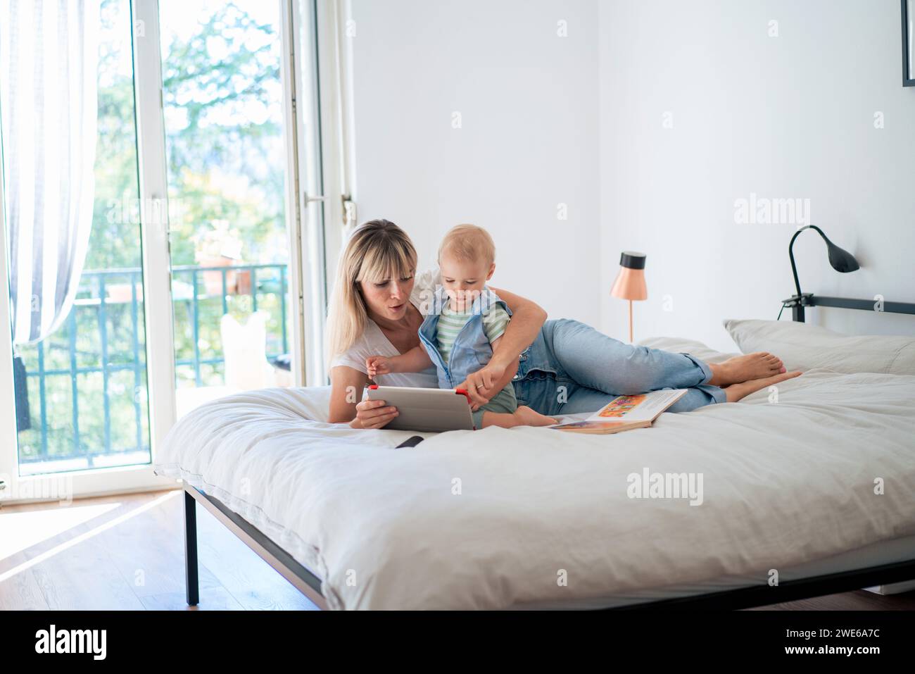 Mother lying on bed and using tablet PC with son at home Stock Photo