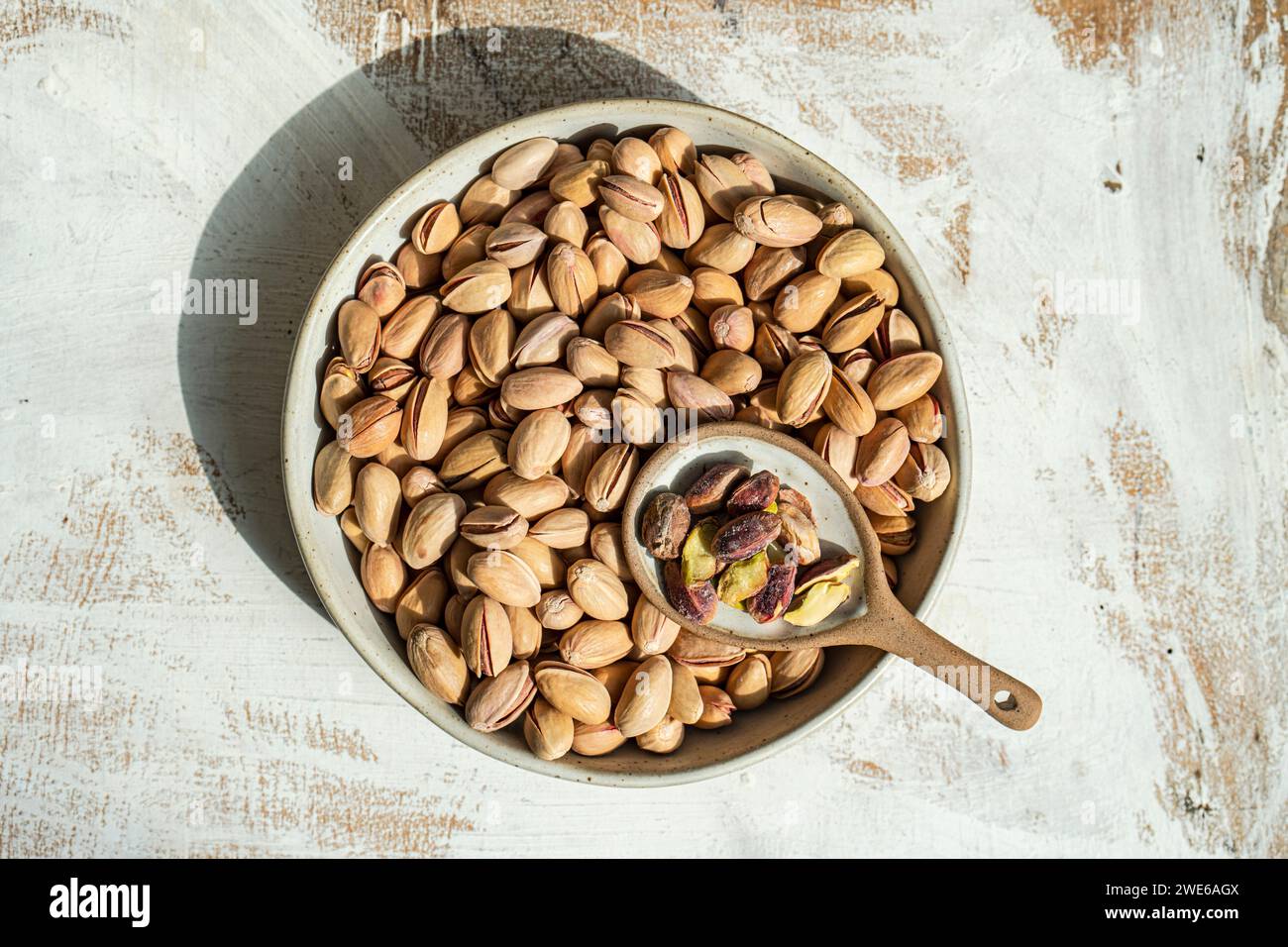 Organic pistachios in a ceramic bowl on a rustic wooden table Stock Photo