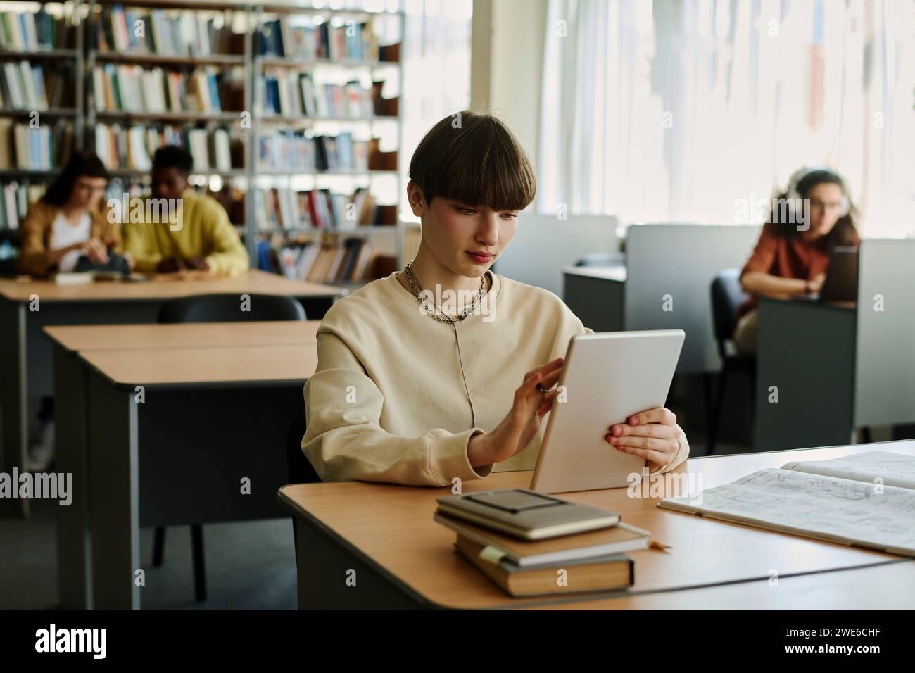 Young student using tablet PC at desk in library Stock Photo