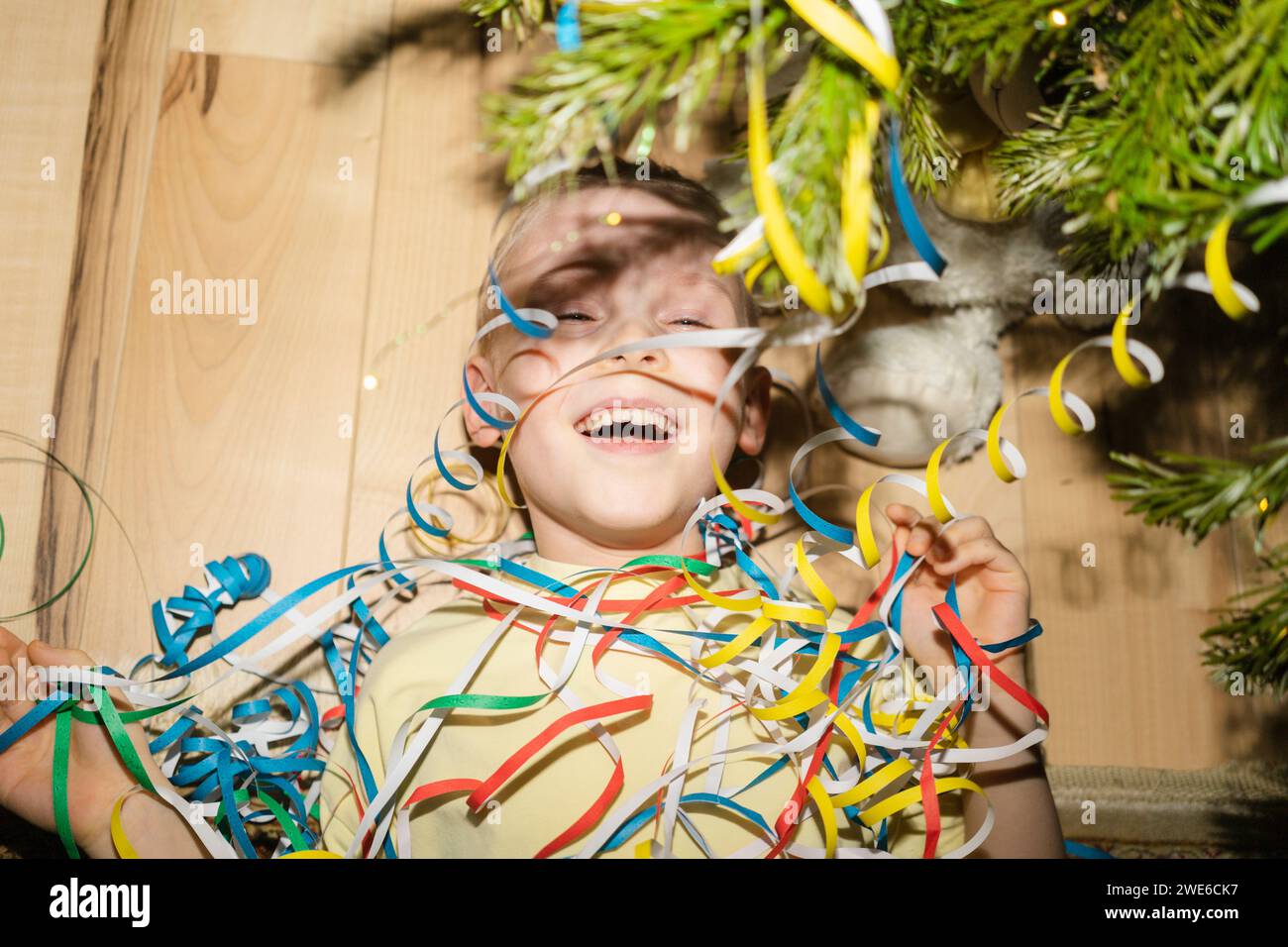 Cheerful boy lying with party poppers at home Stock Photo