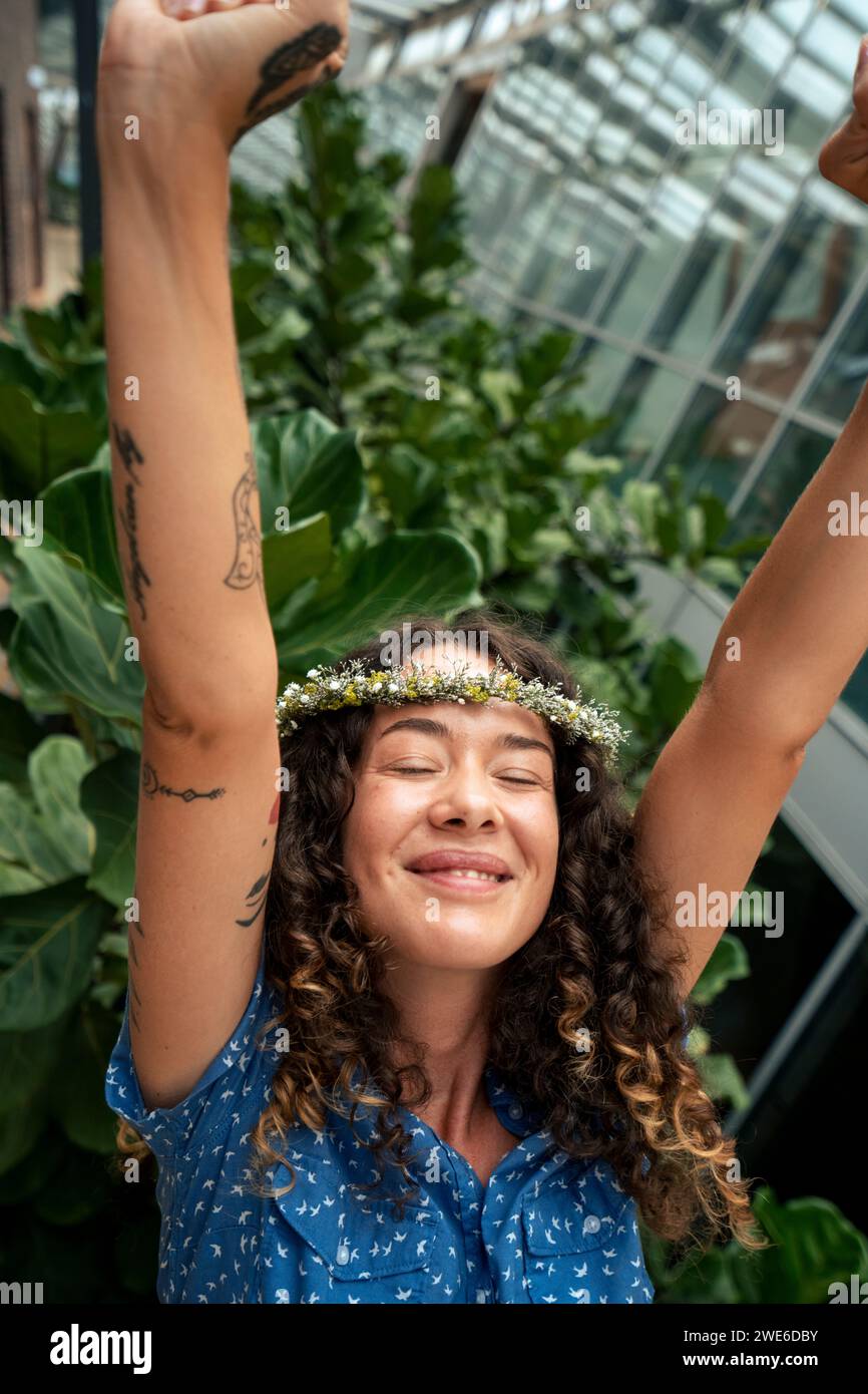 Smiling businesswoman with arms raised wearing tiara in corridor Stock Photo