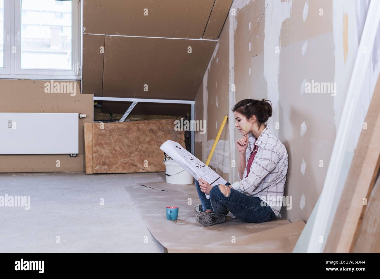 Young woman reading blueprint for home development Stock Photo