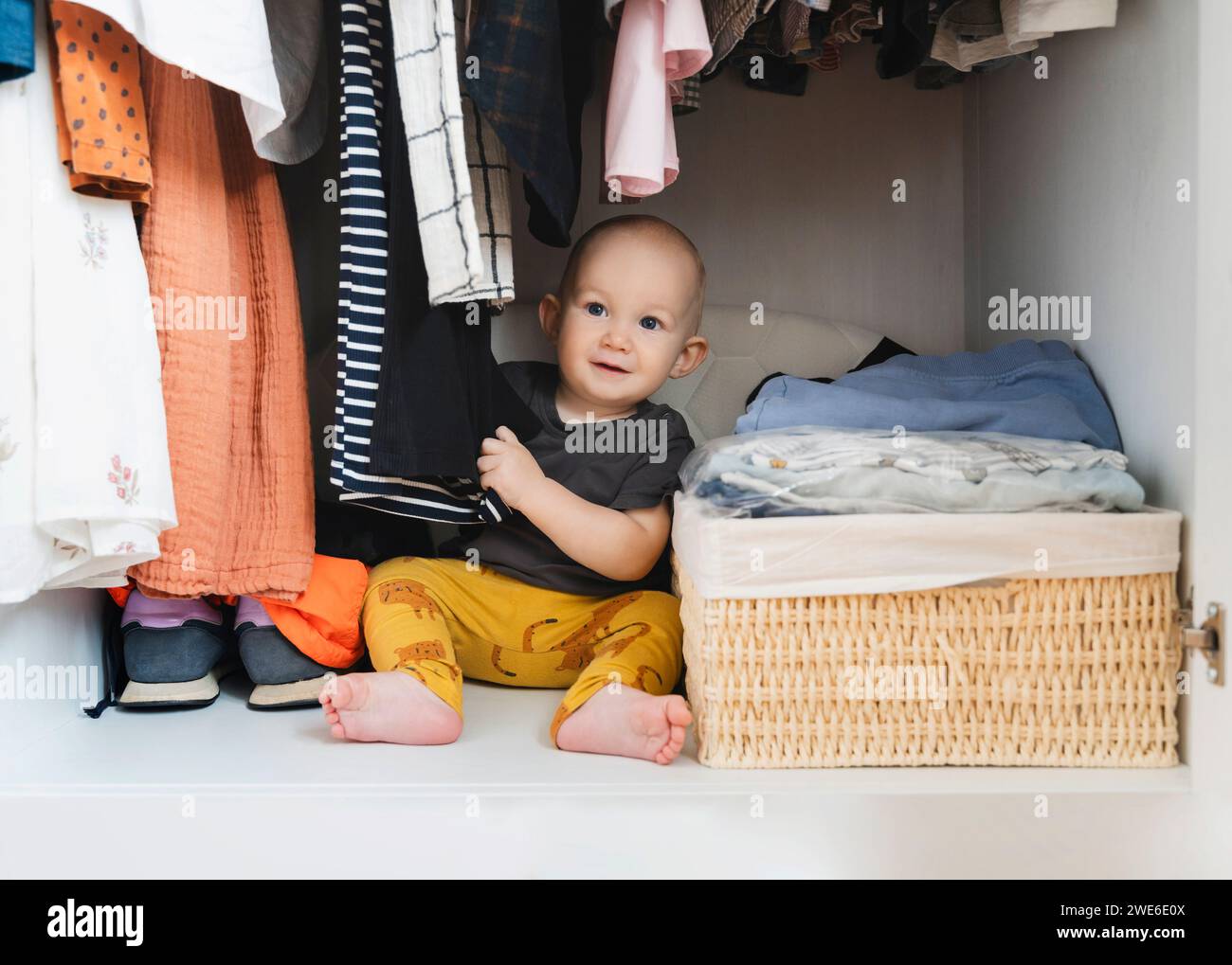 Cute boy playing with clothes in closet at home Stock Photo
