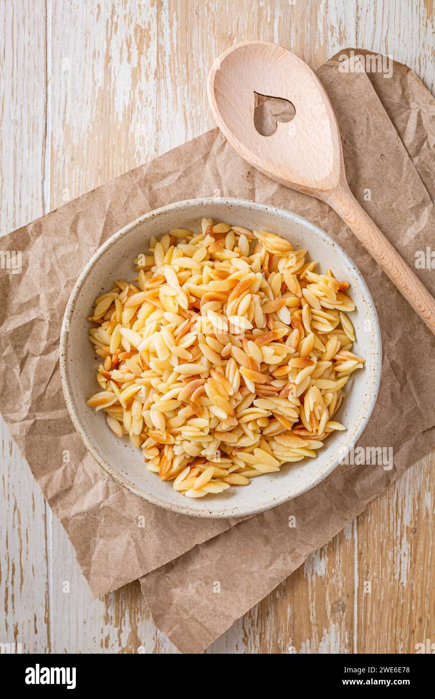 Cooked italian pasta, risoni, orzo in a bowl on wooden table Stock Photo