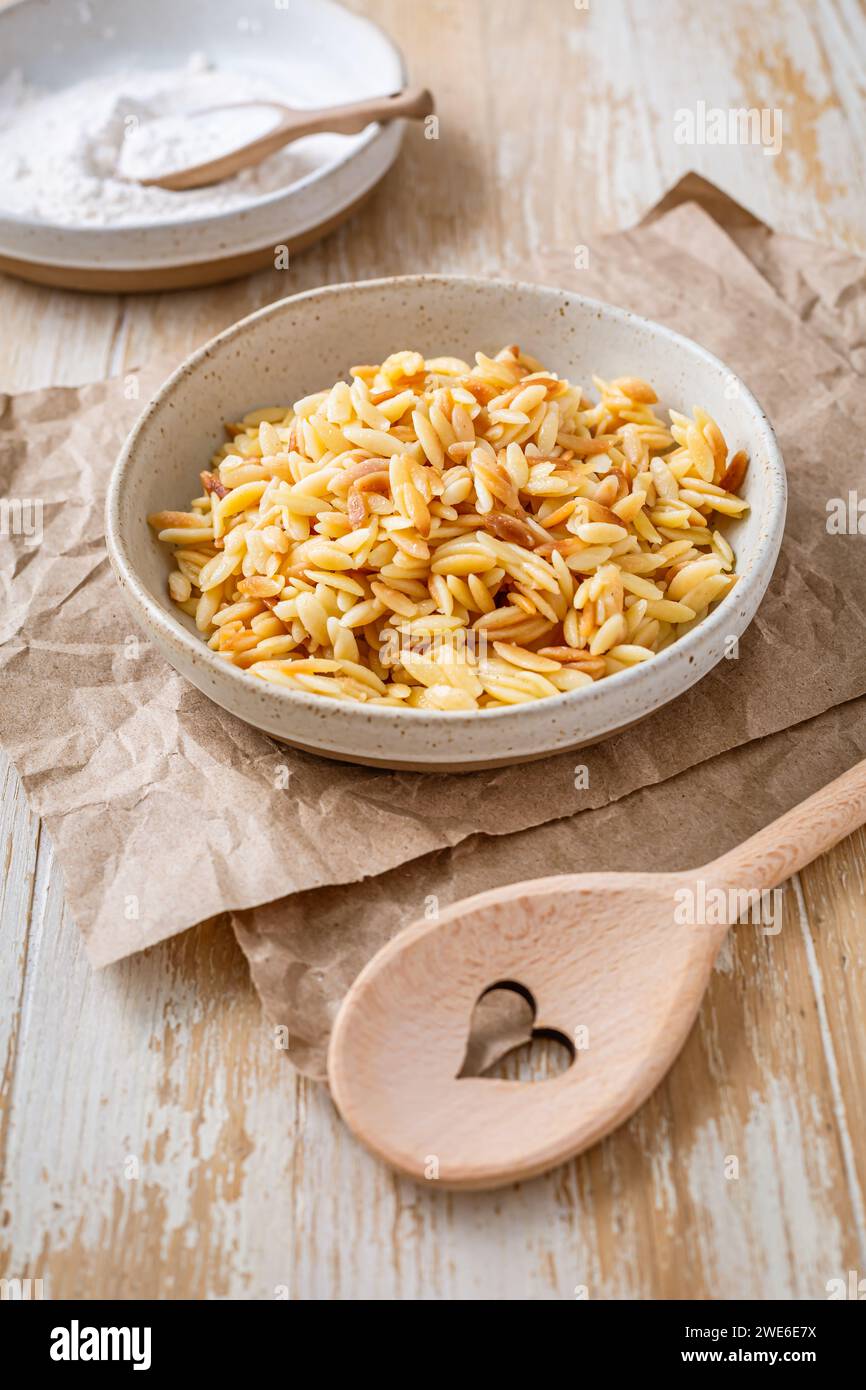 Cooked italian pasta, risoni, orzo in a bowl on wooden table Stock Photo