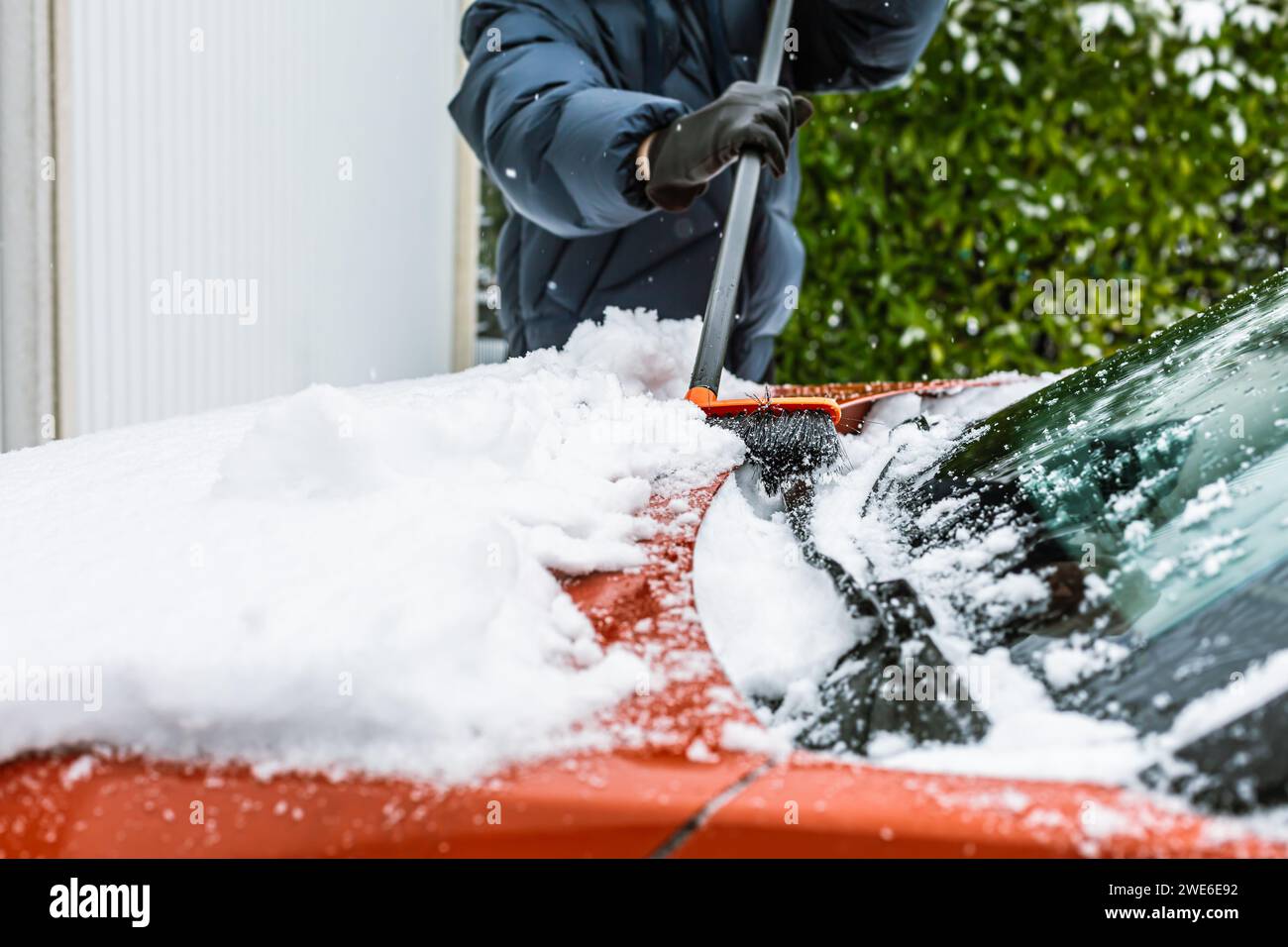 Cleaning snow from windshield. Cleaning and clearing the car from snow on a winter day. Stock Photo