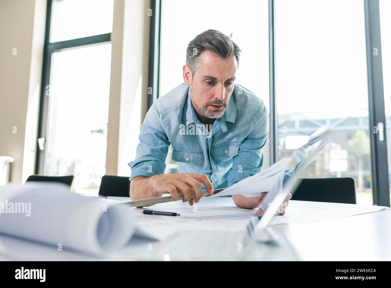 Architect leaning on desk and working with documents in office Stock Photo