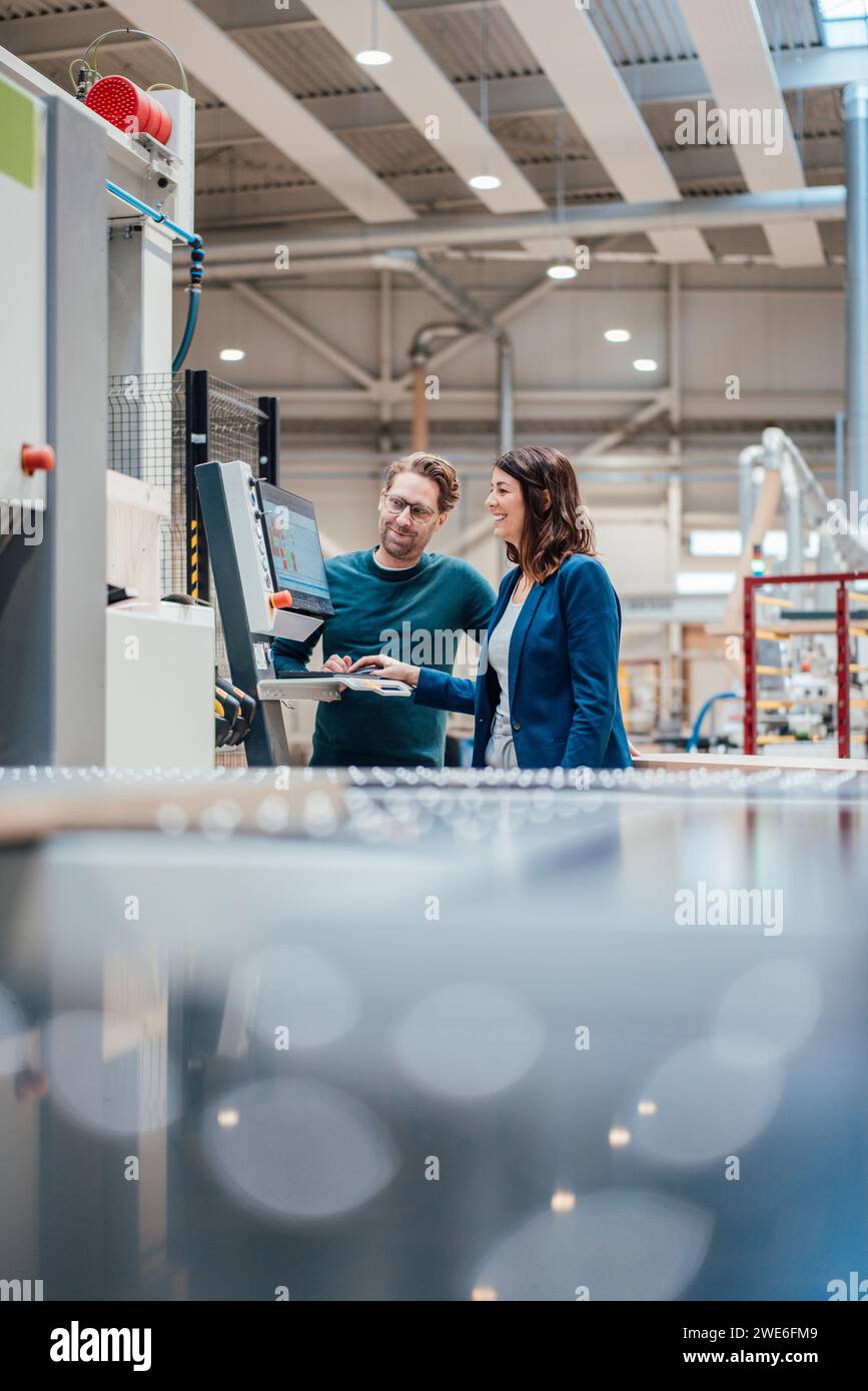 Colleagues discussing over computer standing in industry Stock Photo
