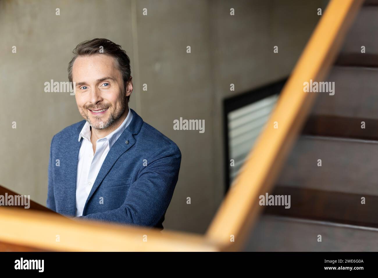 Smiling mature businessman wearing blazer by staircase Stock Photo