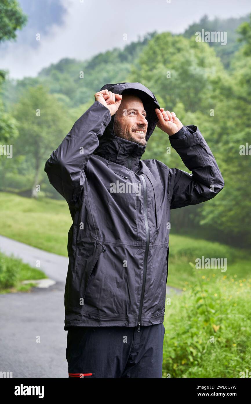 Happy man wearing black jacket and standing in front of trees Stock ...