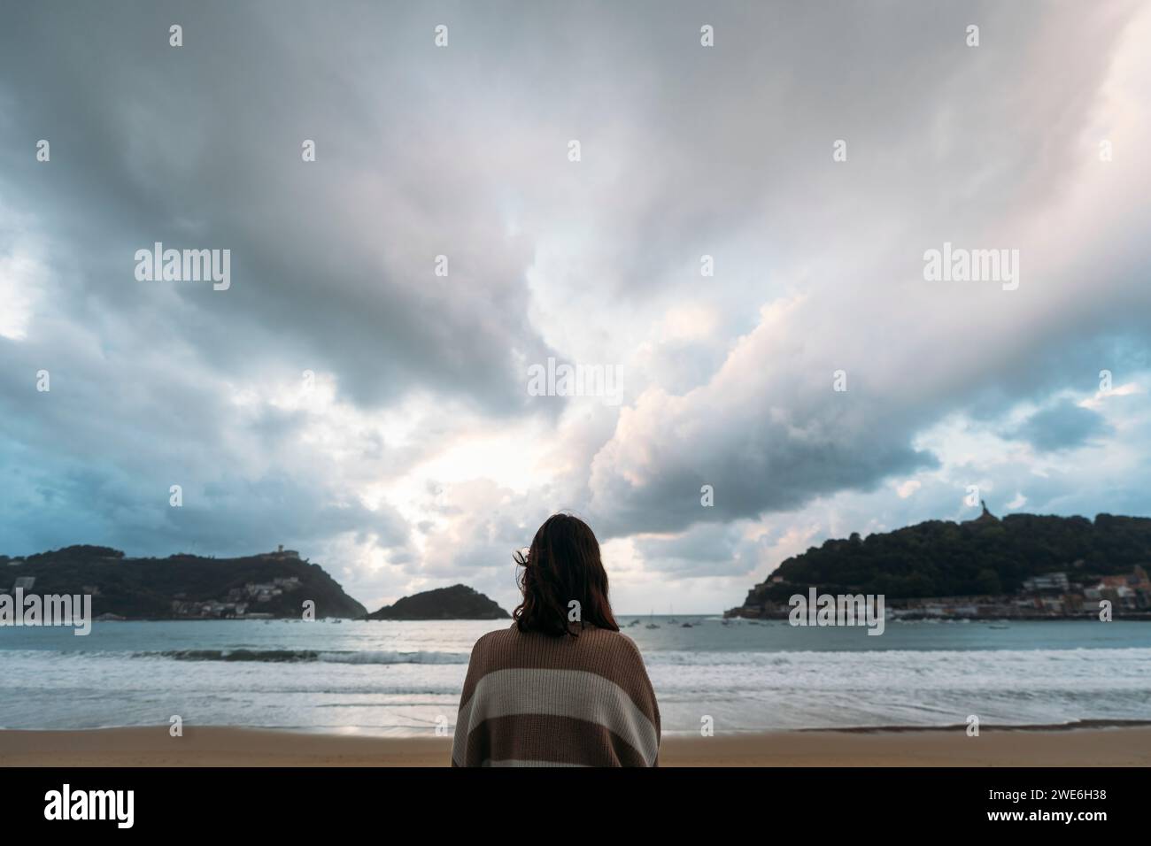 Young woman at Playa de la Concha under cloudy sky Stock Photo